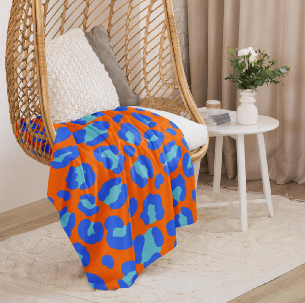 Bold leopard print fleece throw blanket. Bold orange and blue leopard print pattern.